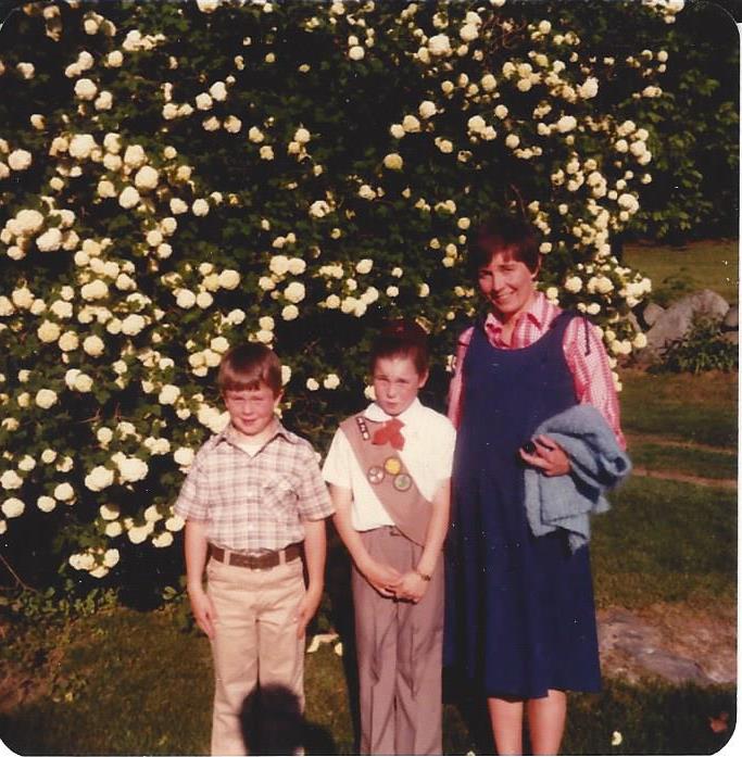 Maura Healey with her mother and brother on a grassy lawn.