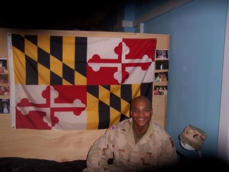 Wes Moore in his Army uniform with a Maryland state flag behind him.